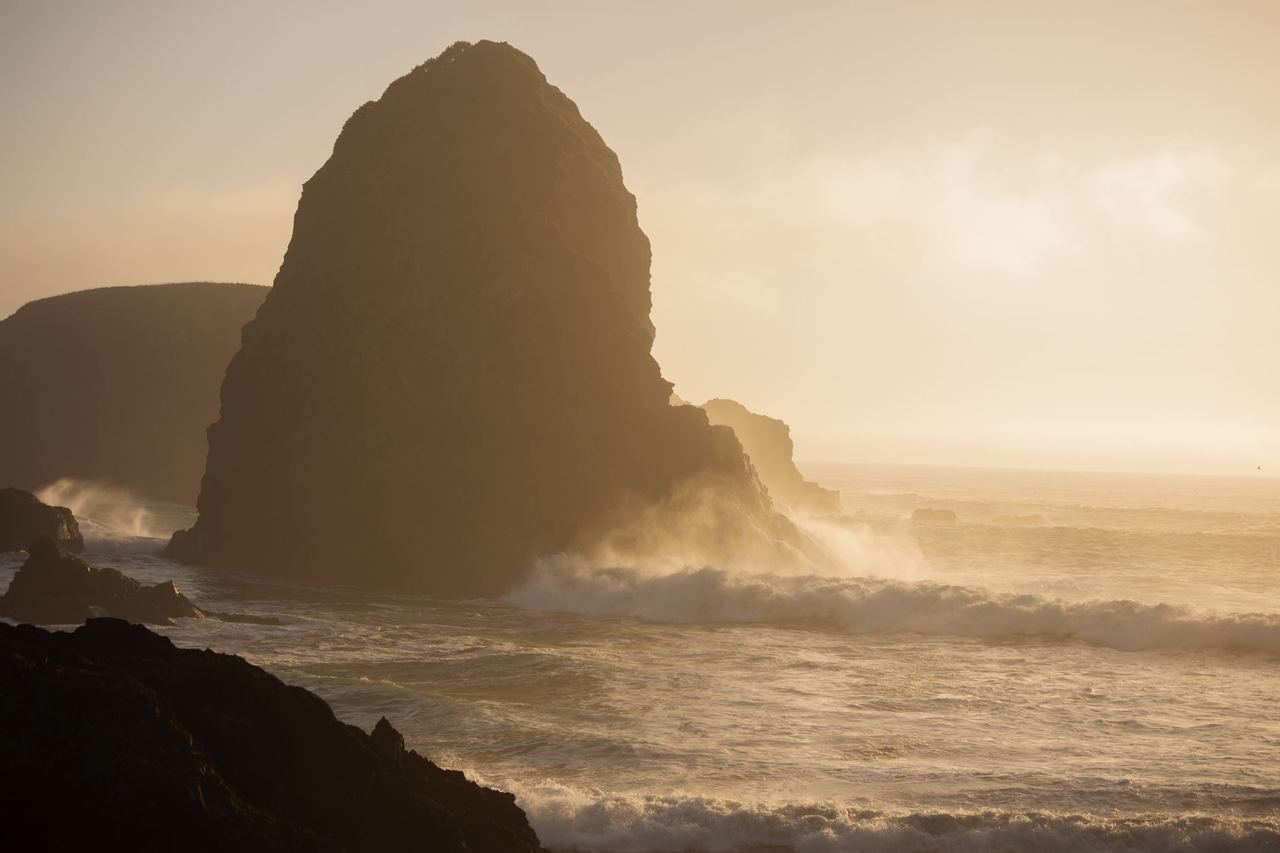 Sunset behind a sea stack and breaking surf at Brookings, Oregon